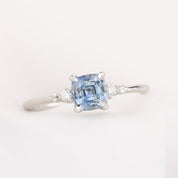 white gold ring with blue light blue cushion cut montana sapphire, with two natural accent diamonds on white background