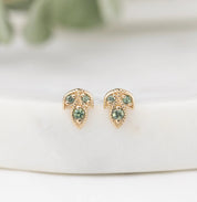 Gold earrings with green gemstones on a white surface