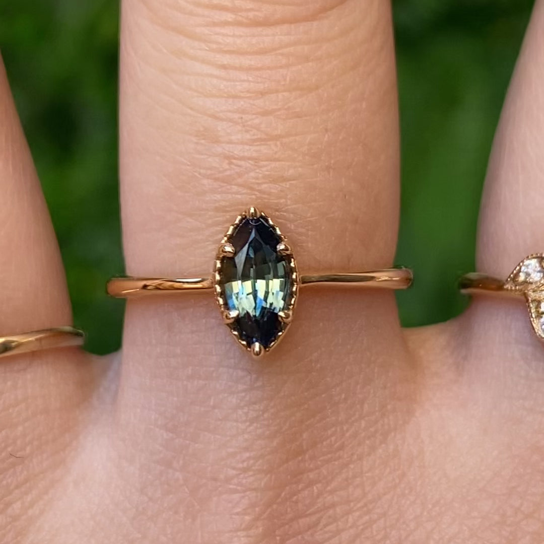 Video of Ava Ring, 0.85ct Blue Green Madagascar Sapphire, Marquise Cut on 14k yellow gold setting on a hand shown in natural lighting
