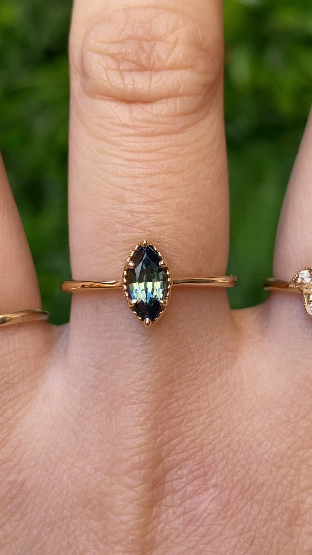 Video of Ava Ring, 0.85ct Blue Green Madagascar Sapphire, Marquise Cut on 14k yellow gold setting on a hand shown in natural lighting