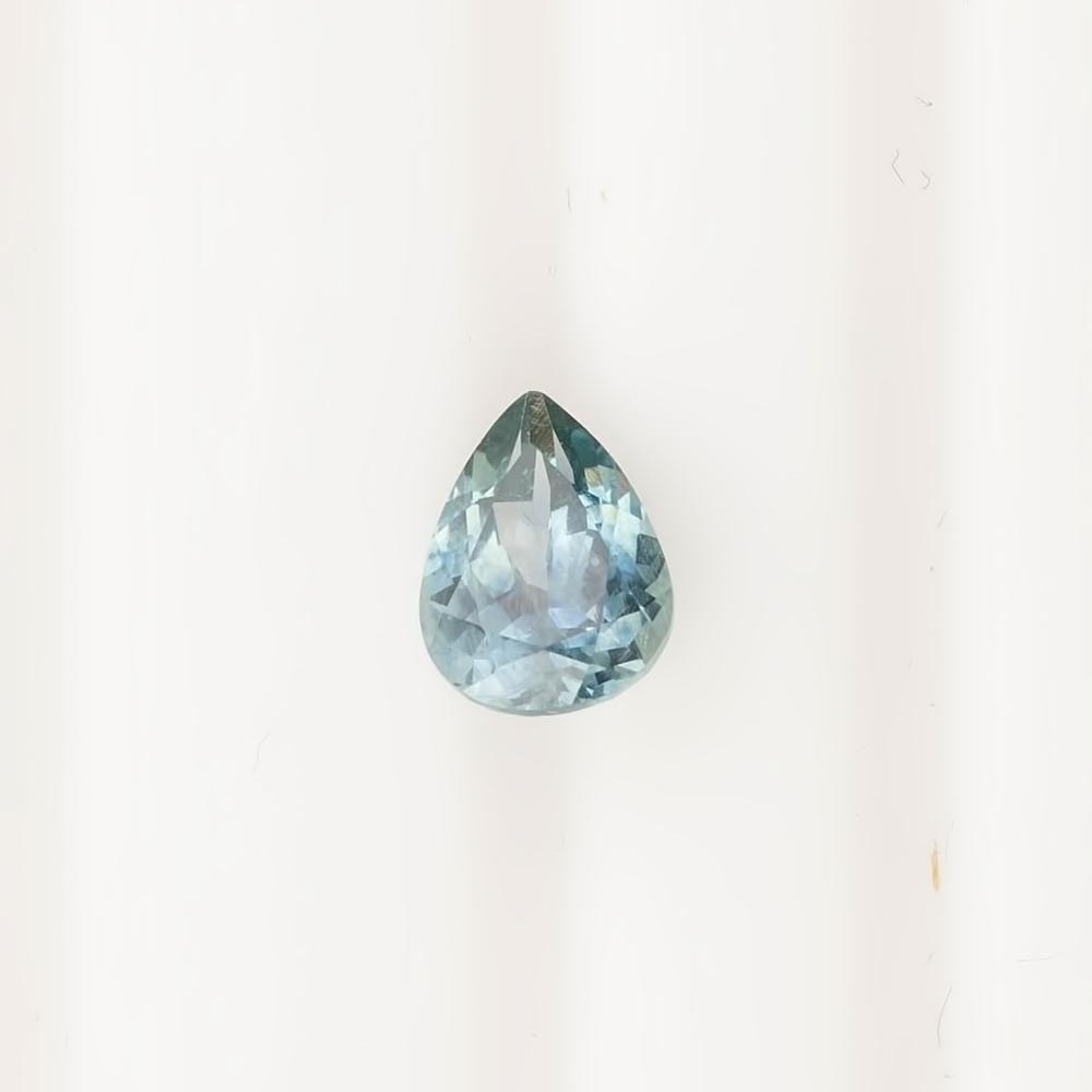 1.41ct pear-shaped Montana sapphire in blue green with medium teal saturation and precise cut on white background