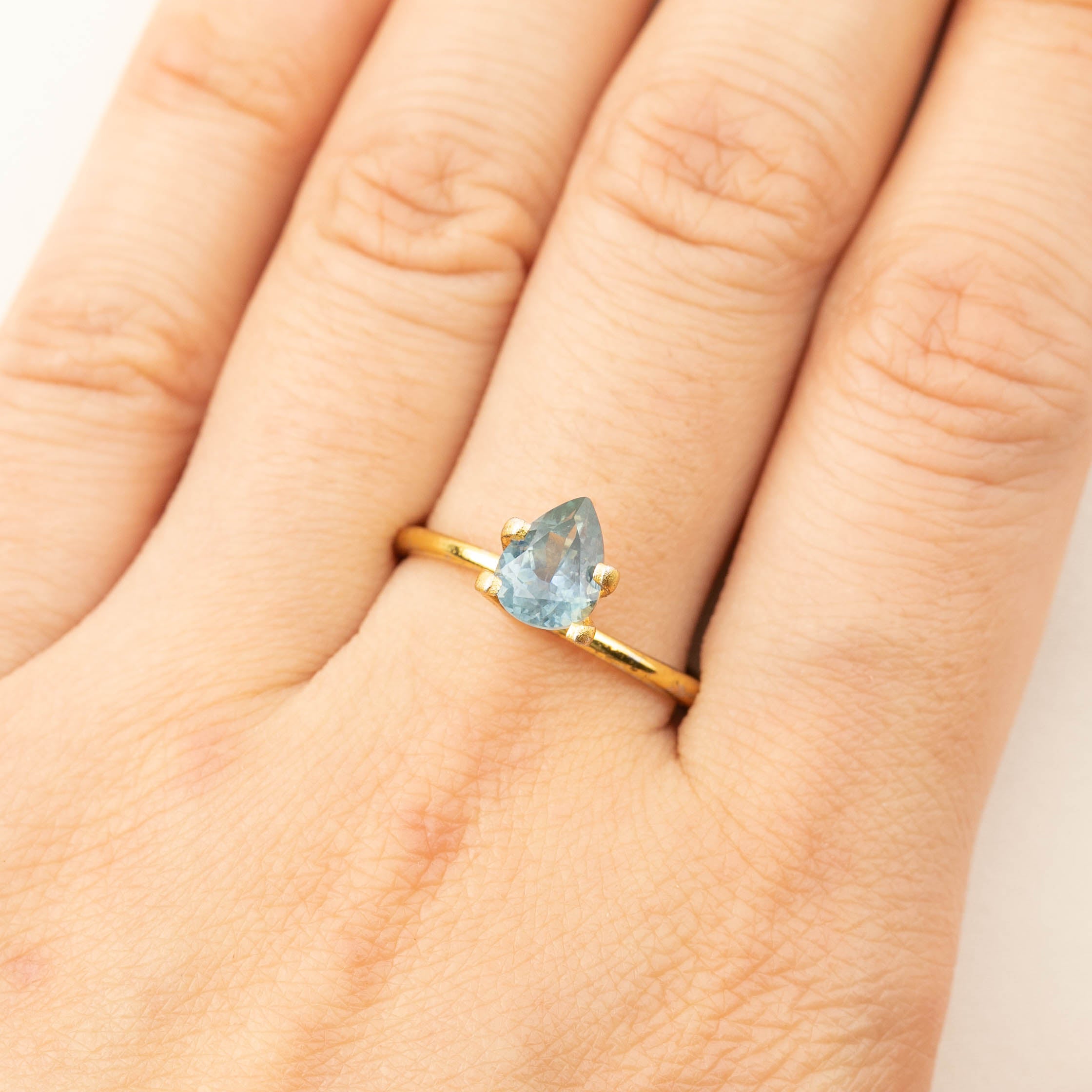 1.41ct pear-shaped Montana sapphire ring in gold setting on finger with medium teal blue color