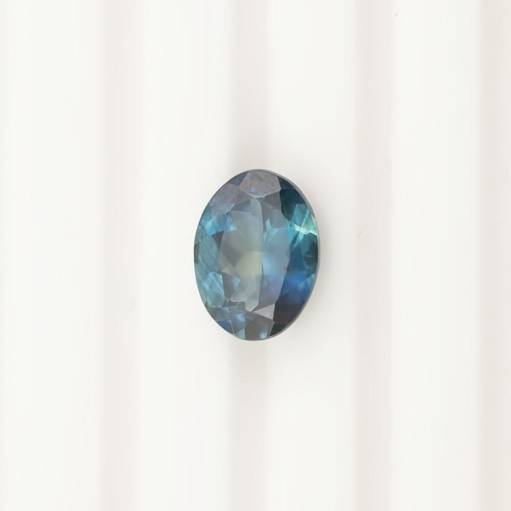 1.62ct oval cut teal blue Montana sapphire gemstone with eye-clean clarity and small inclusions visible under magnification