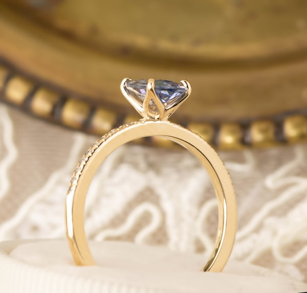 Close-up of 14k gold ring featuring a 1.07ct teal blue Montana sapphire with diamond accents in a floral setting.