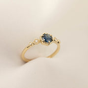 Delicate 14k gold ring featuring a 0.7ct Queensland peacock sapphire with accent diamonds in a bezel setting.