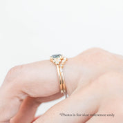 Celine Ring featuring a 0.60ct teal-blue Montana sapphire in a 14k yellow gold with six natural diamond accents on a hand showing side view with a band