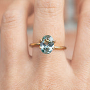 1.85ct Oval Cut Light Blue Green Montana Sapphire SO197 set in a delicate gold ring on finger, handmade jewelry style
