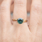 1.58ct Round Cut Green Montana Sapphire ring worn on finger with gold band, authentic and ethically sourced gemstone