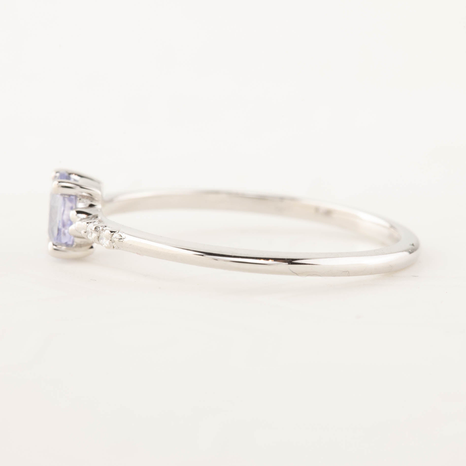 Side view of a 0.45ct unheated oval sapphire set in 14k gold with a sparkling diamond pave band.