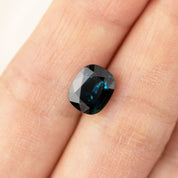 3.39ct cushion cut teal blue sapphire from Sri Lanka with VVS clarity and heat treatment shown on finger