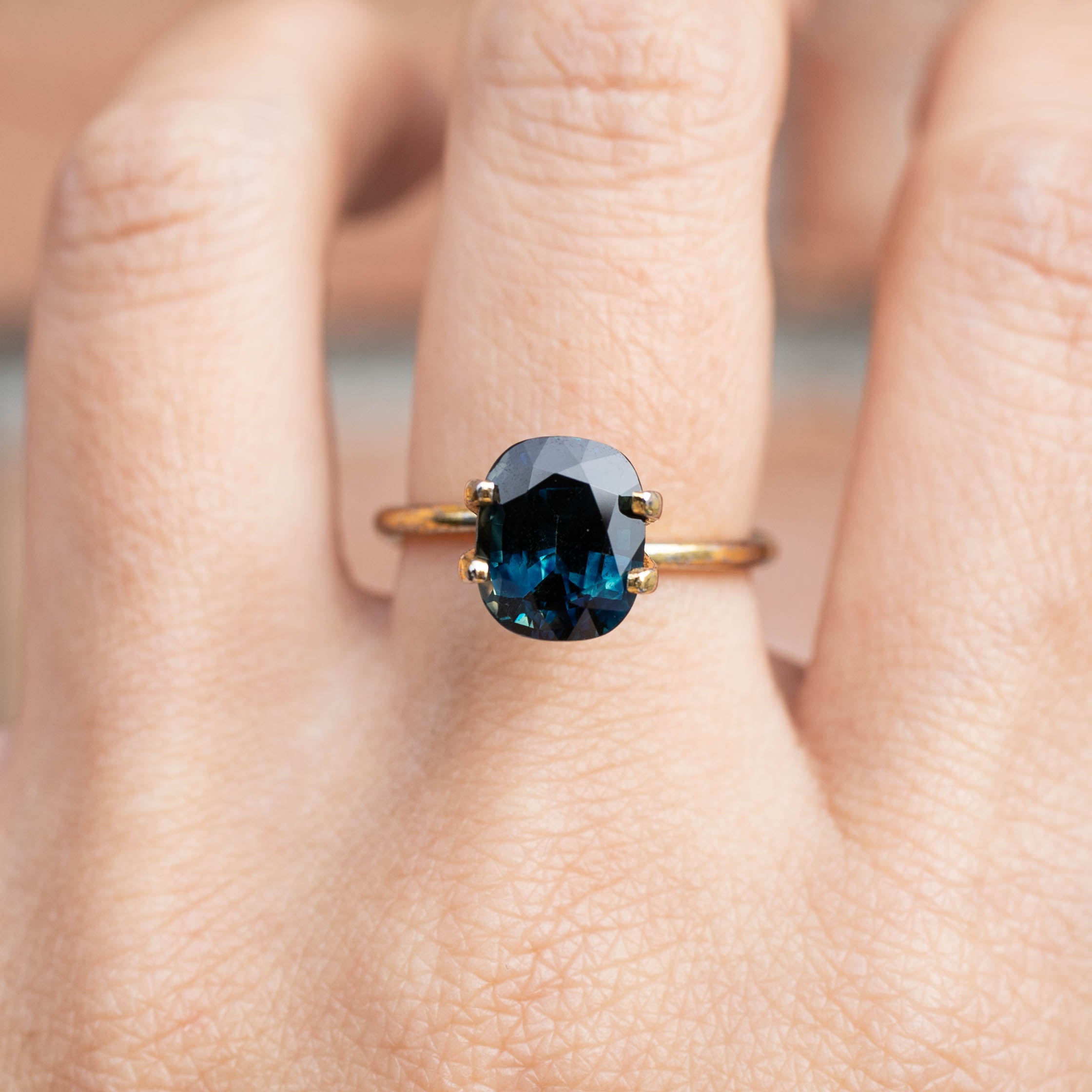3.39ct cushion cut teal sapphire ring with gold band showcased on finger, Sri Lanka origin gemstone