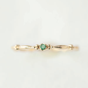 Delicate 14k yellow gold ring with a small green gemstone, featuring a thin 1.75mm recycled metal band design.