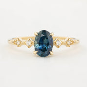 A teal blue 1.21ct Montana sapphire ring with accent diamonds set in a 14k yellow gold band
